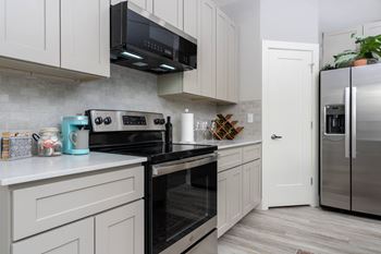 A kitchen with white cabinets and black appliances.